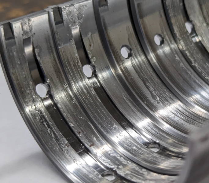 Close-up of metal grooves with holes, possibly part of a mechanical component.