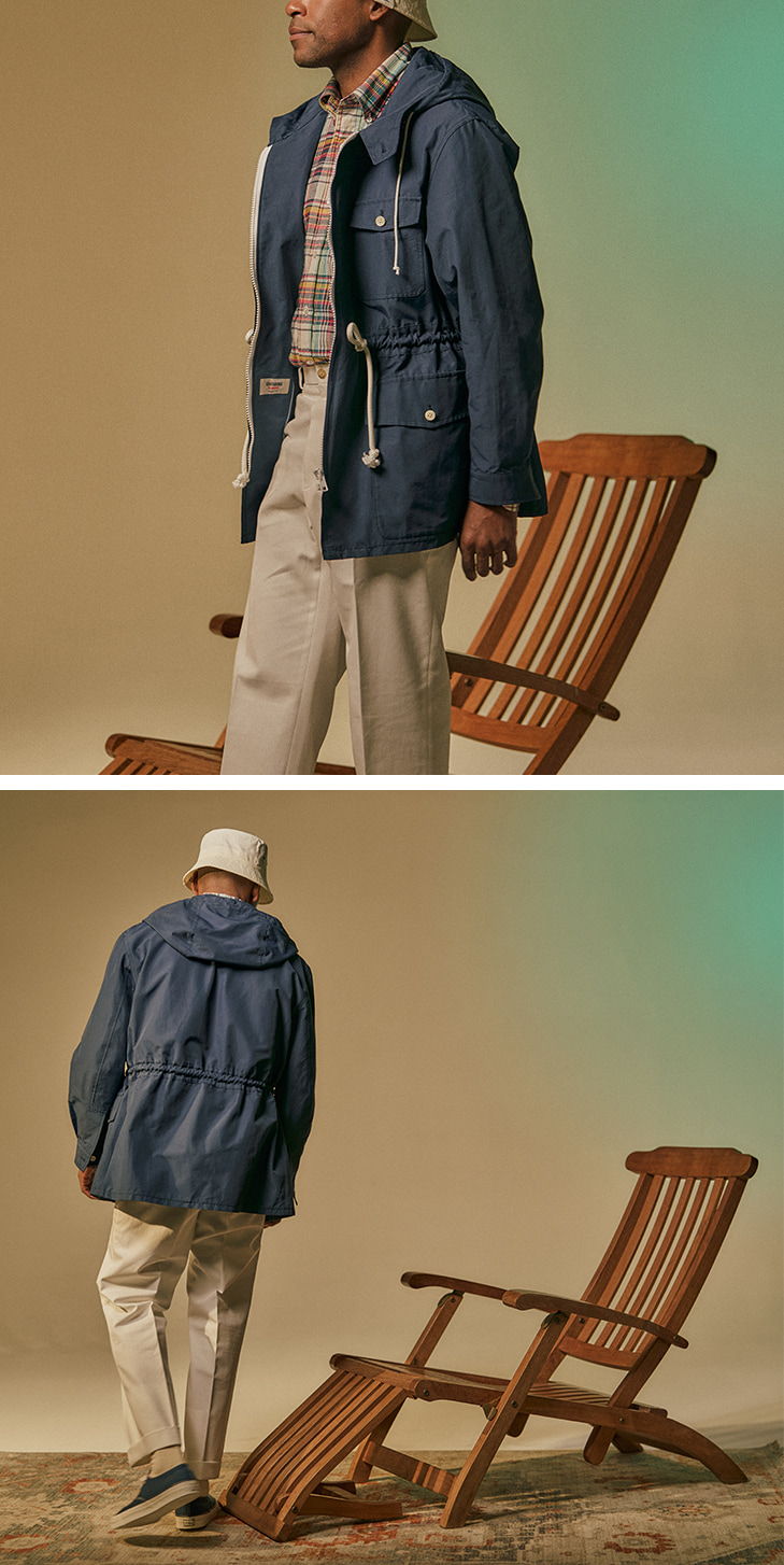 Person wearing a blue jacket and pants stands next to a wooden chair.
