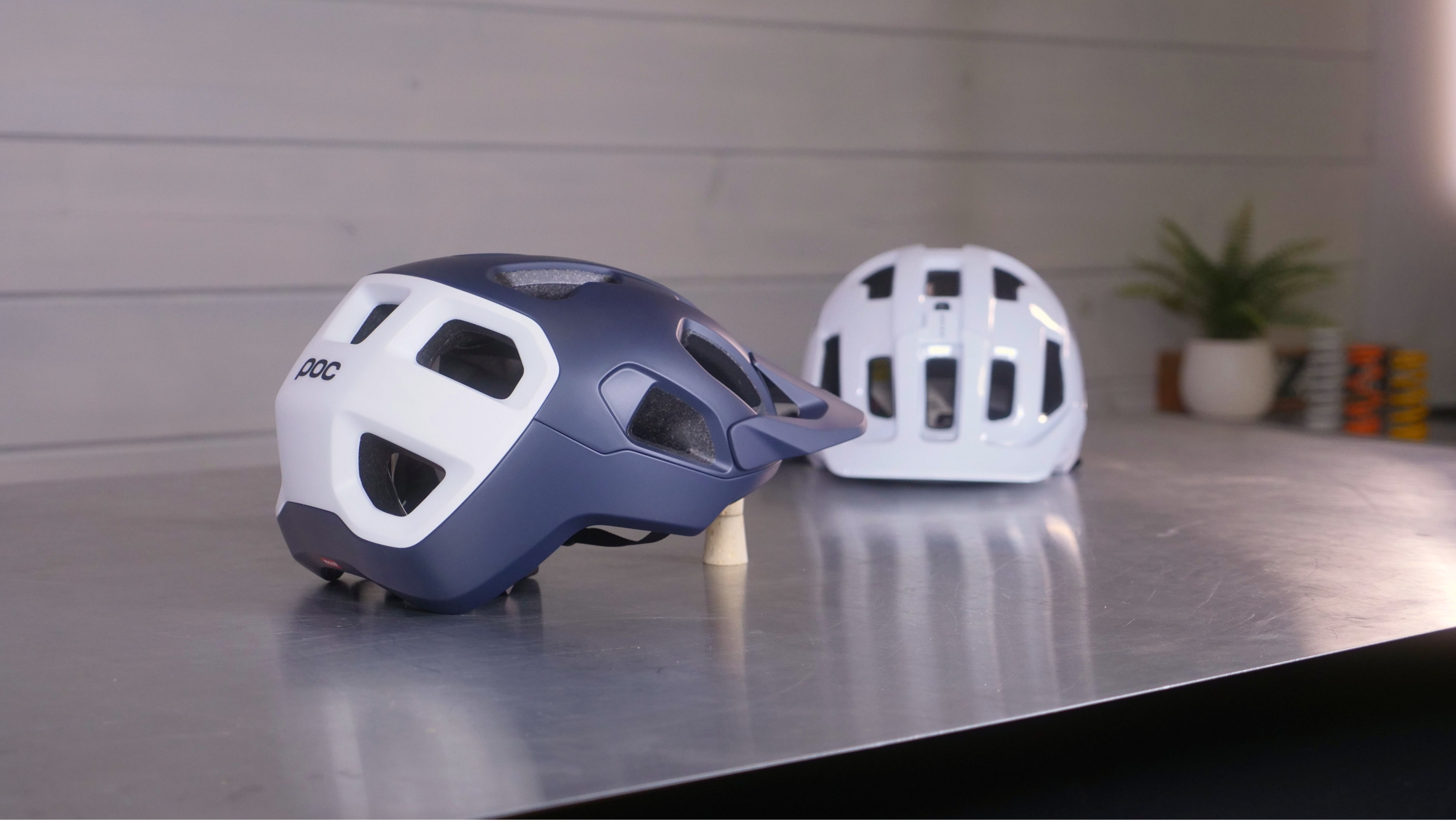 Two bicycle helmets, one blue and one white, on a table.