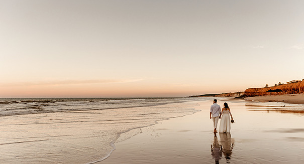 A married couple walking on an Oregon beach during a sunset