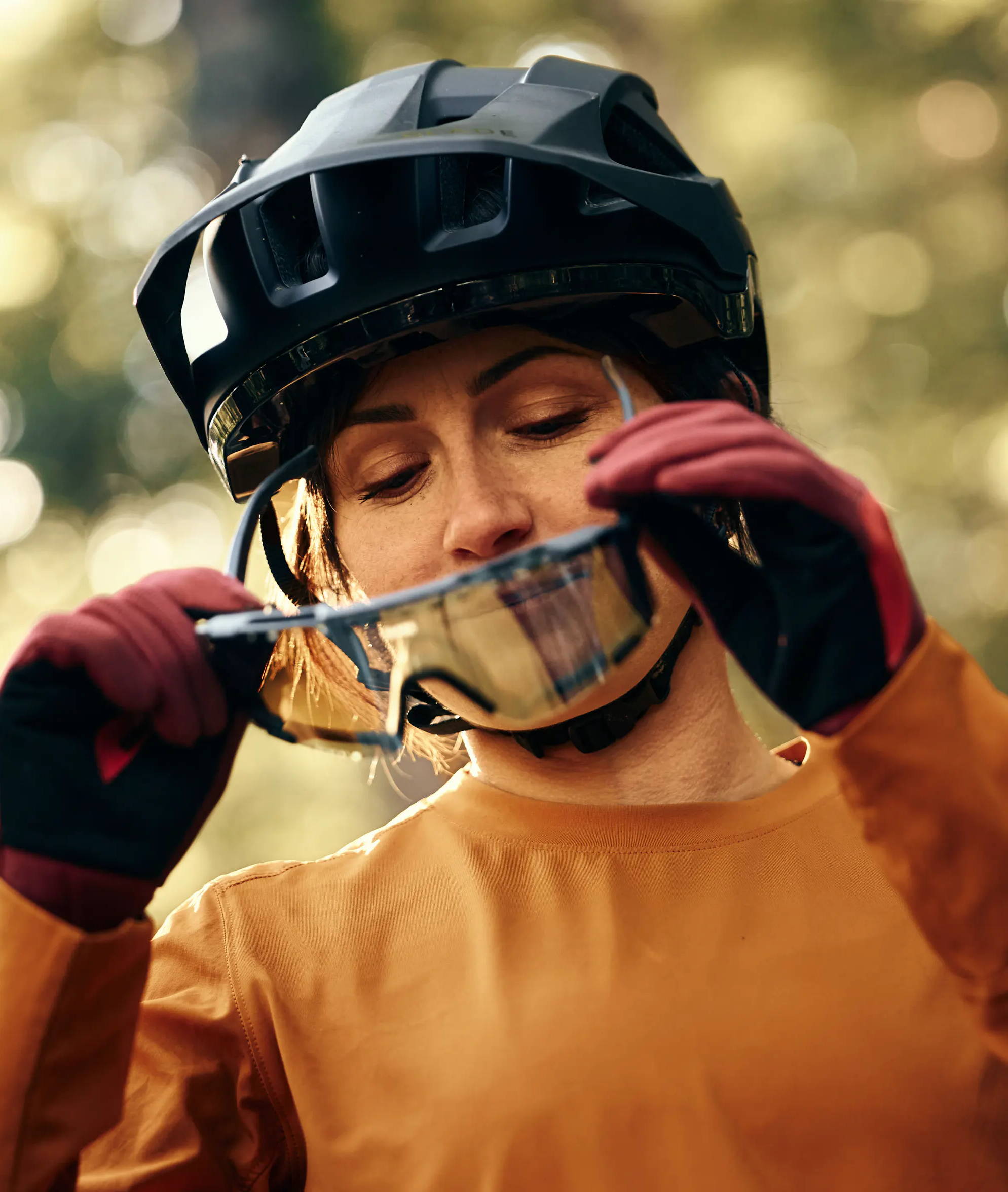 Person adjusting sunglasses while wearing a helmet and outdoor gear.