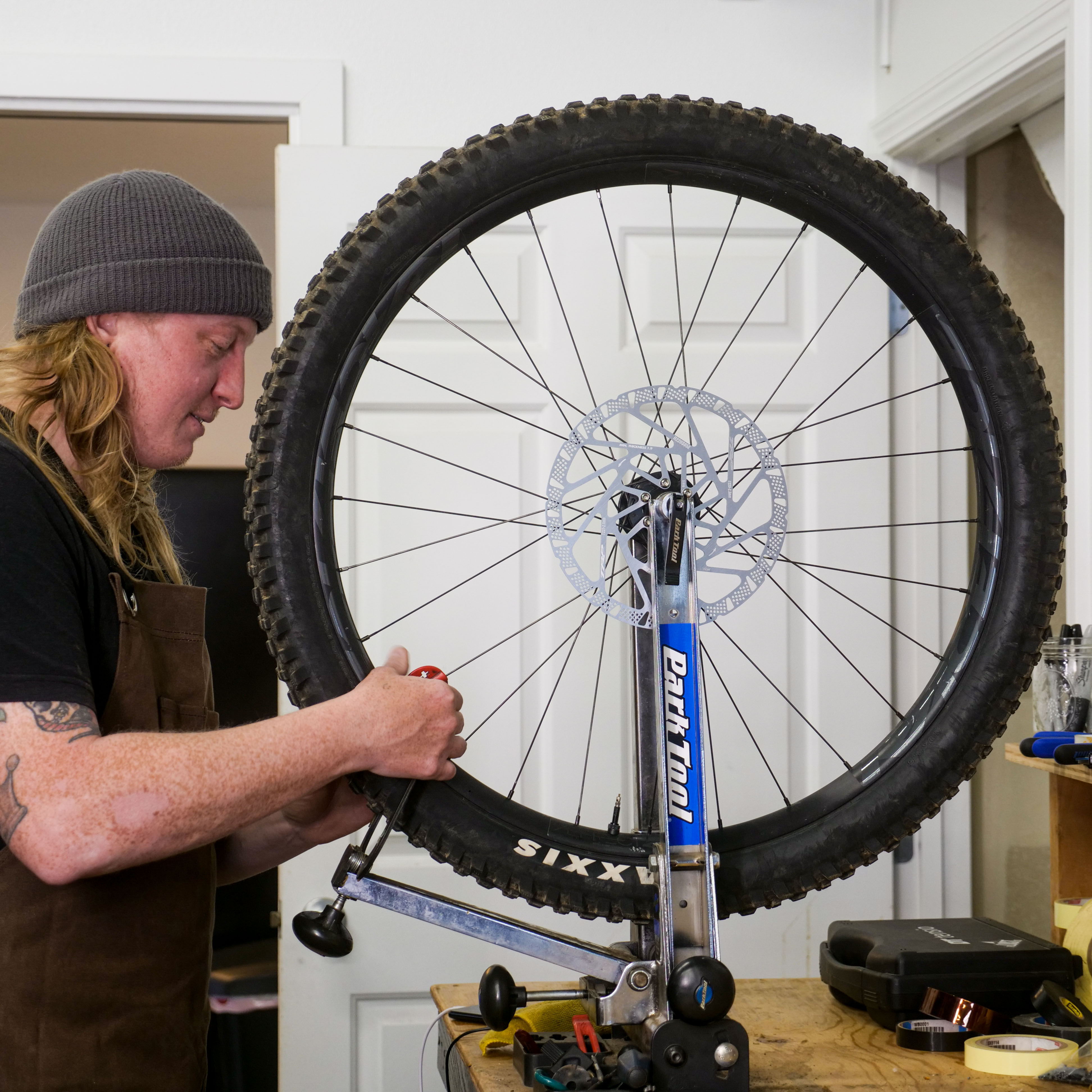 Person repairing a bike wheel in a workshop.