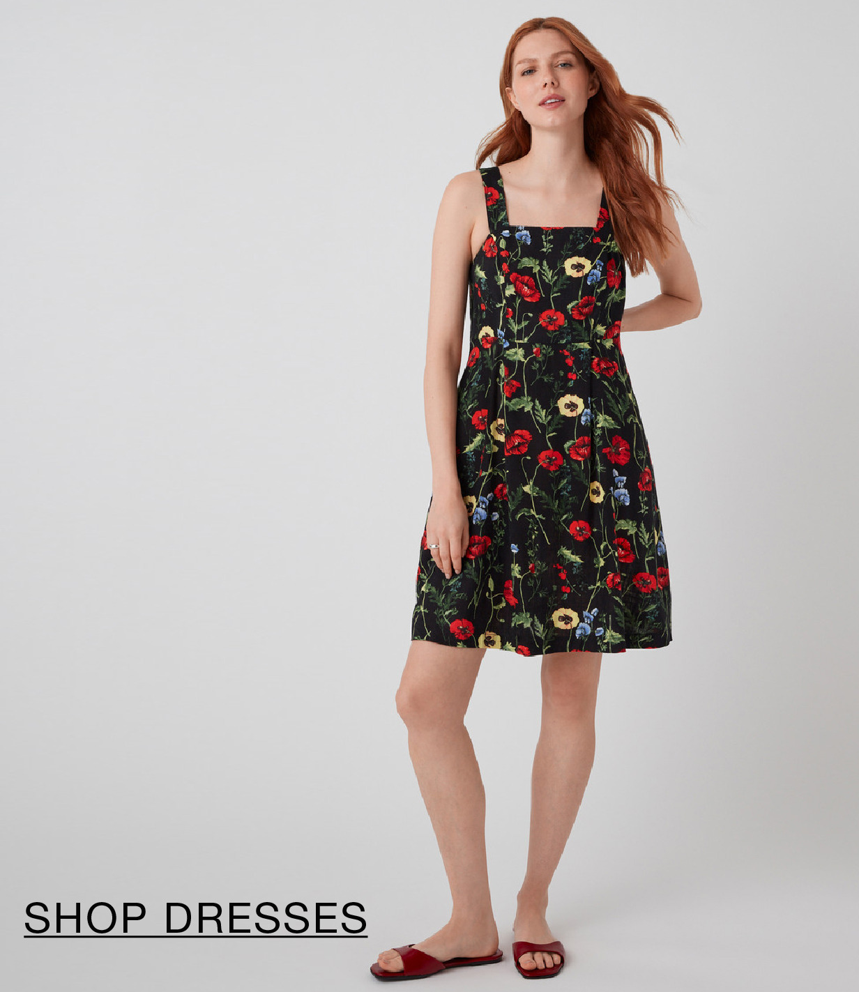 Model wearing a floral dress with a black background, standing against a light backdrop.