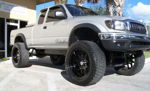 Low-angle front-quarter silver lifted Toyota Tacoma Xtracab Relentless decal black wheels Blue Parrot Glass palms Wicked Customs 232 featured gallery photo 1