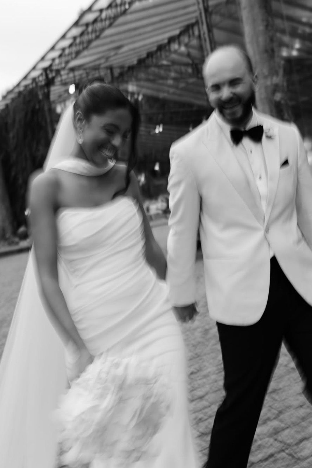 Bride and groom walking together, smiling, in a romantic outdoor setting.