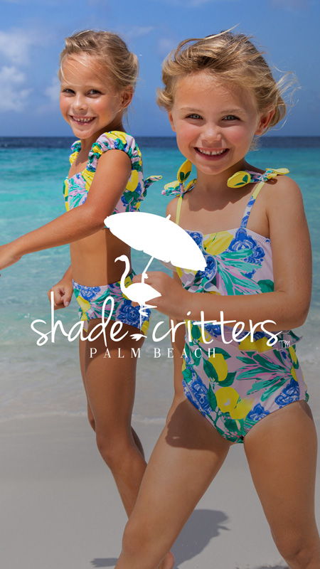 Two girls in colorful swimsuits on a beach.