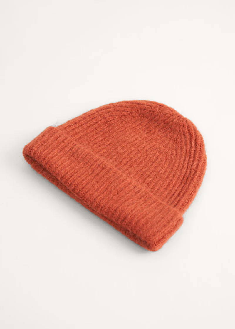 A rust coloured knitted beanie hat