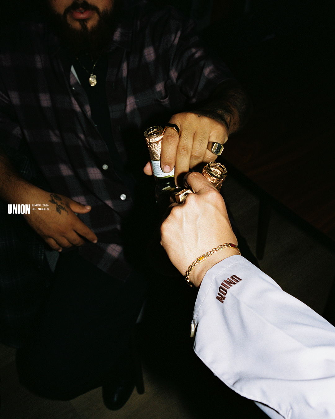 Two hands exchanging an object, adorned with rings and bracelets.