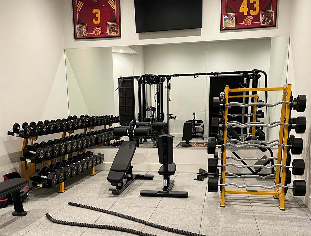 Custom home gym with personalized gold colors on racks and dumbbells