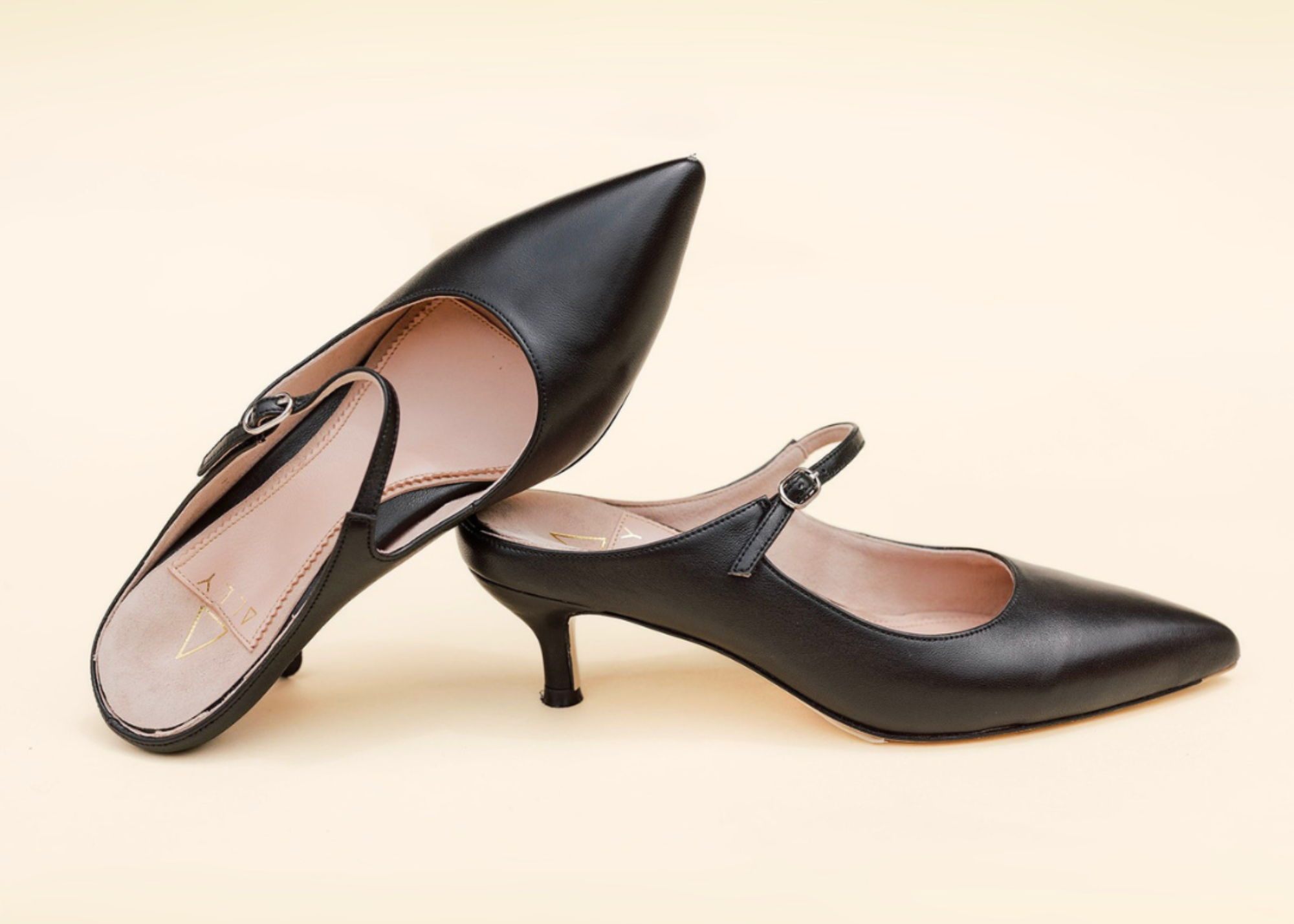 Black slingback high-heeled shoe with a pointed toe and strap.