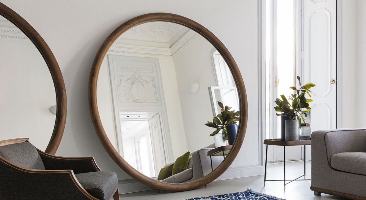 Two round mirrors reflecting a bright, modern living room with a plant.