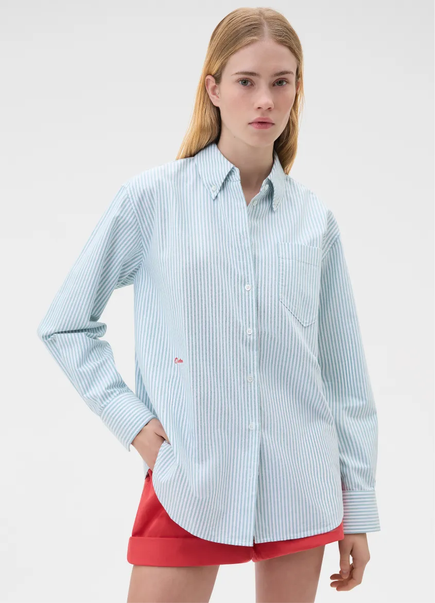Young woman wearing a light blue striped shirt and red shorts.