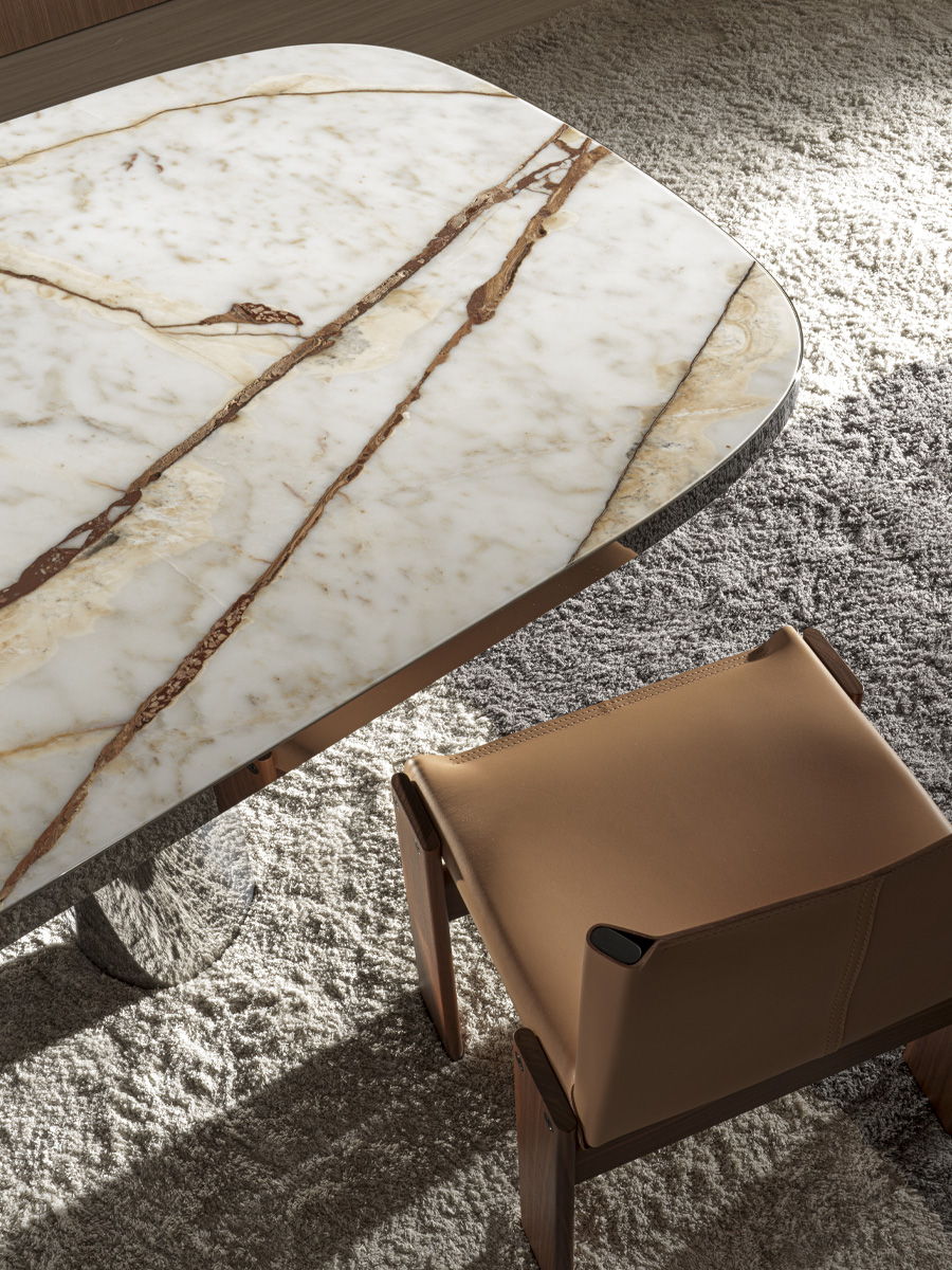 Molteni Marble table with brown veining beside a modern leather chair on a rug.