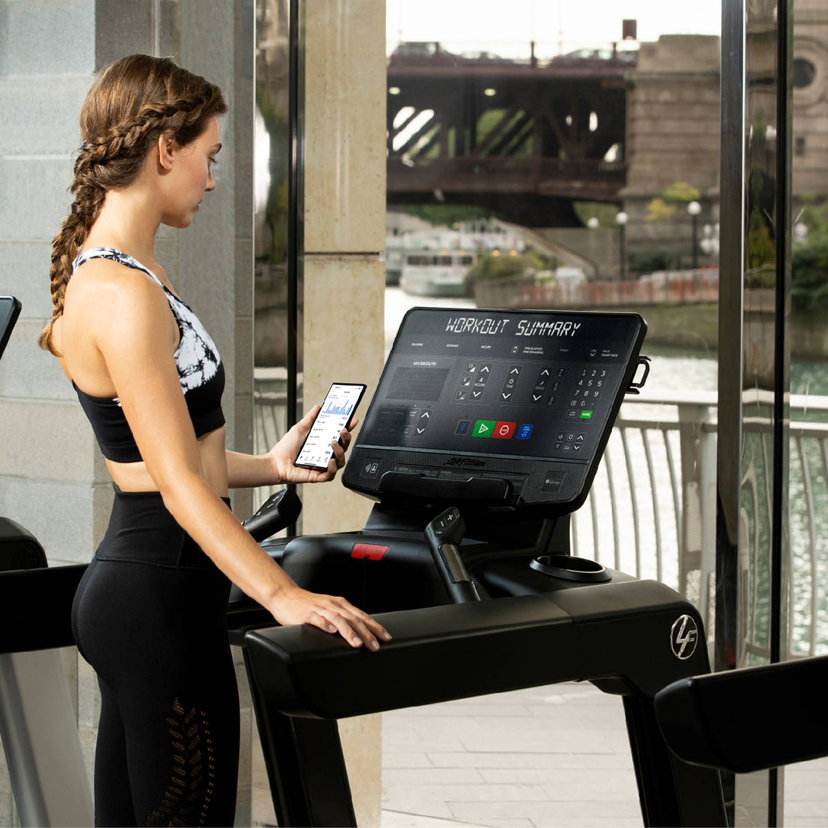 Exerciser looking at Aaptiv app stats on phone on treadmill