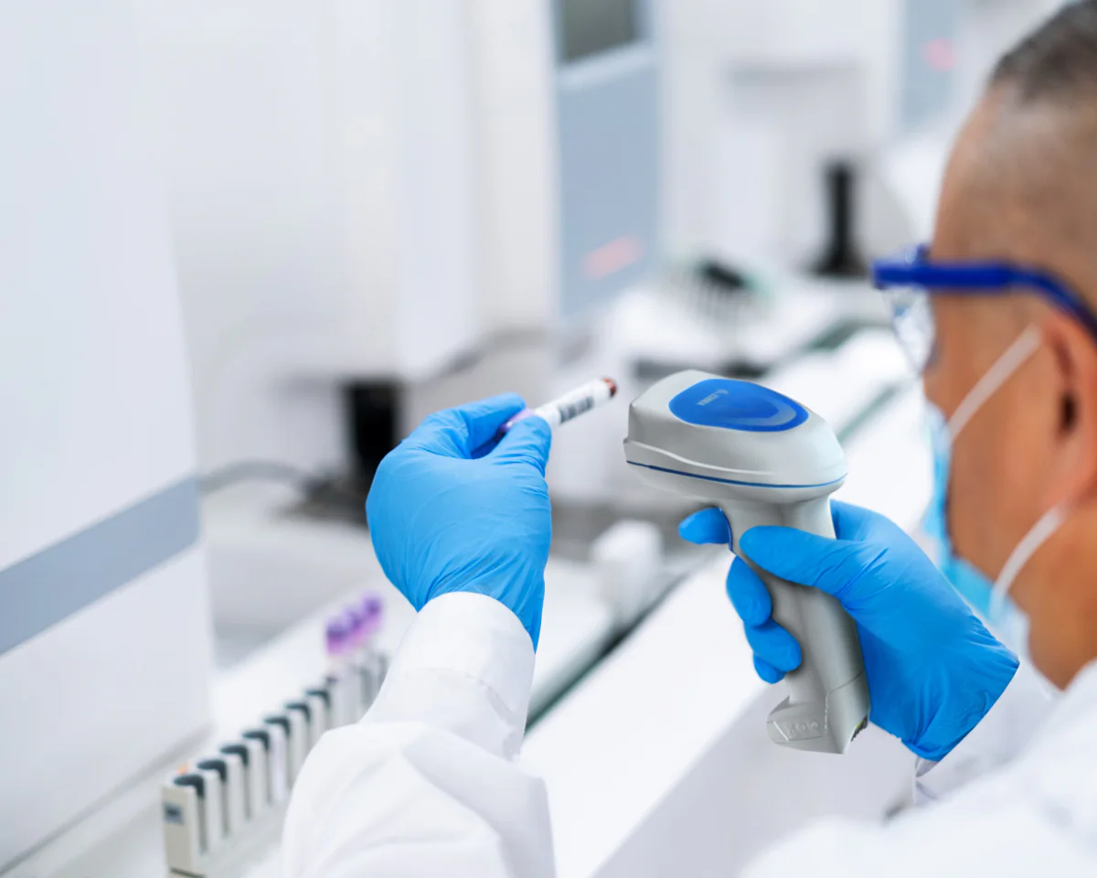 Personal de laboratorio leyendo el código de un tubo de muestra