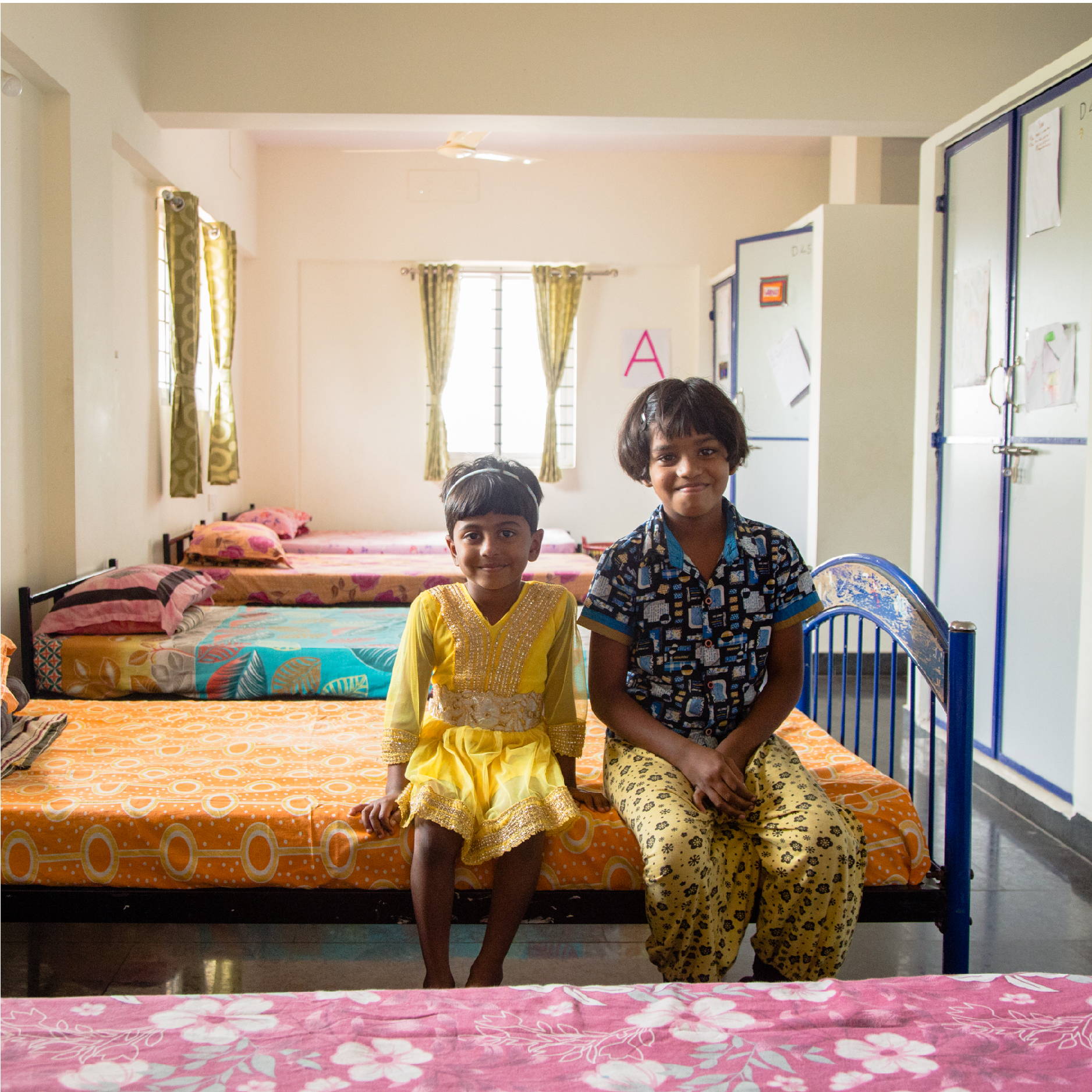 Two Indian girls sit on their beds in a children's home in Bangalore India. 
