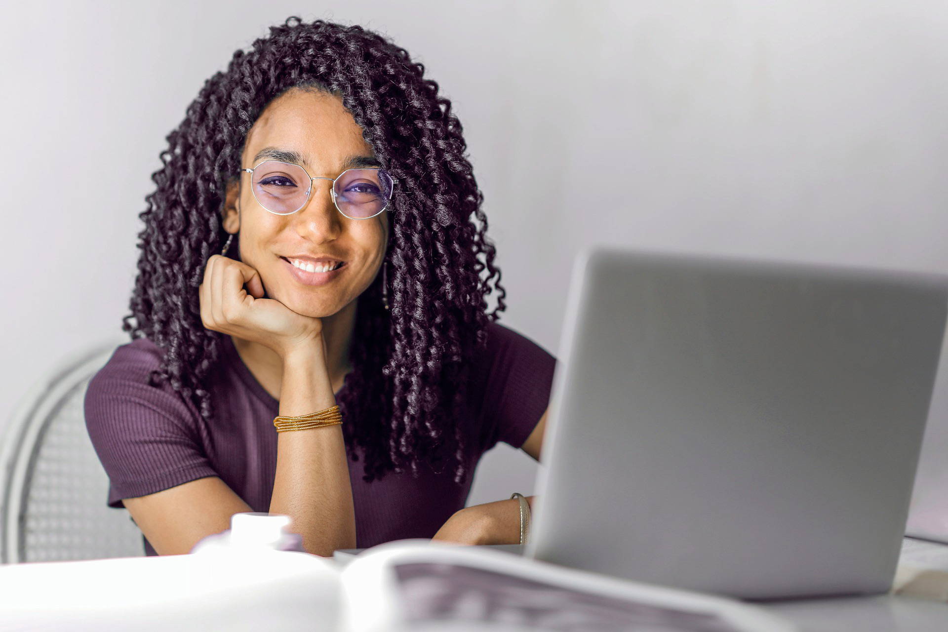 Femme portant des lunettes rondes bloquant la lumière bleue, assise devant l'ordinateur