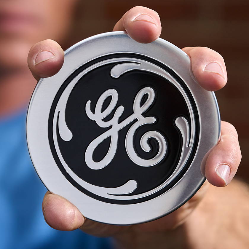 Image of man holding a GE logo badge