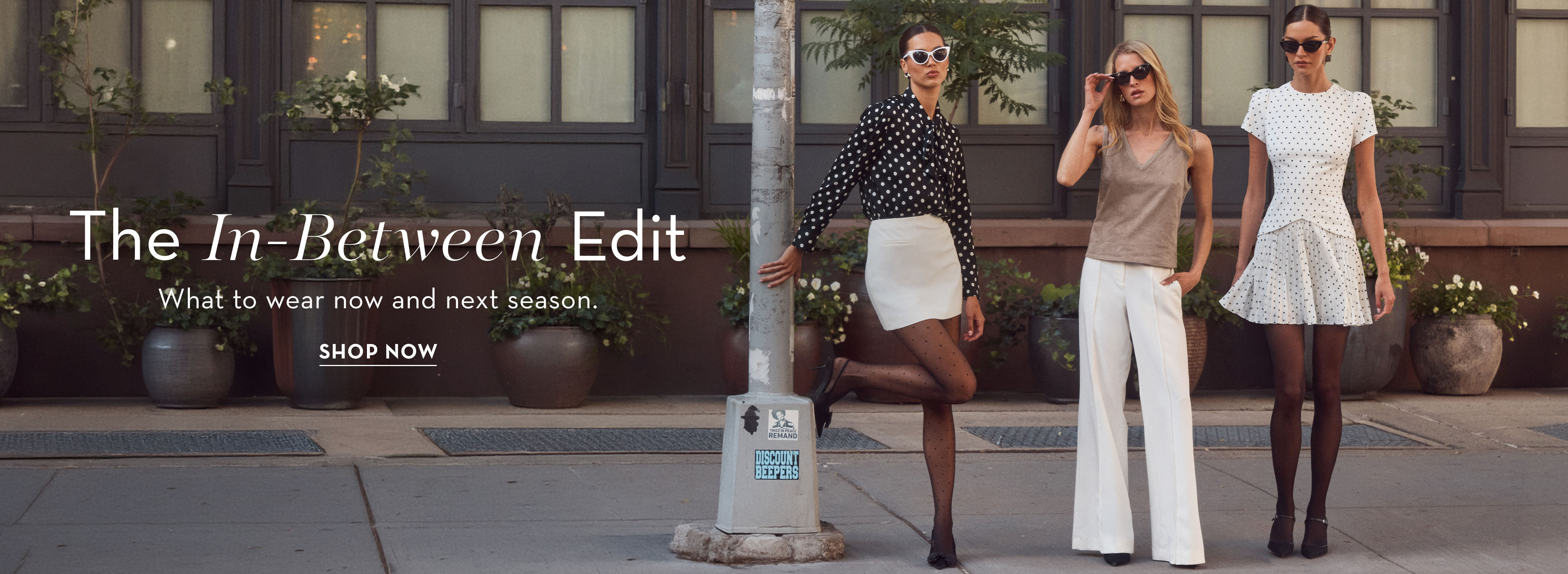 Three women in stylish outfits posing on a city street.