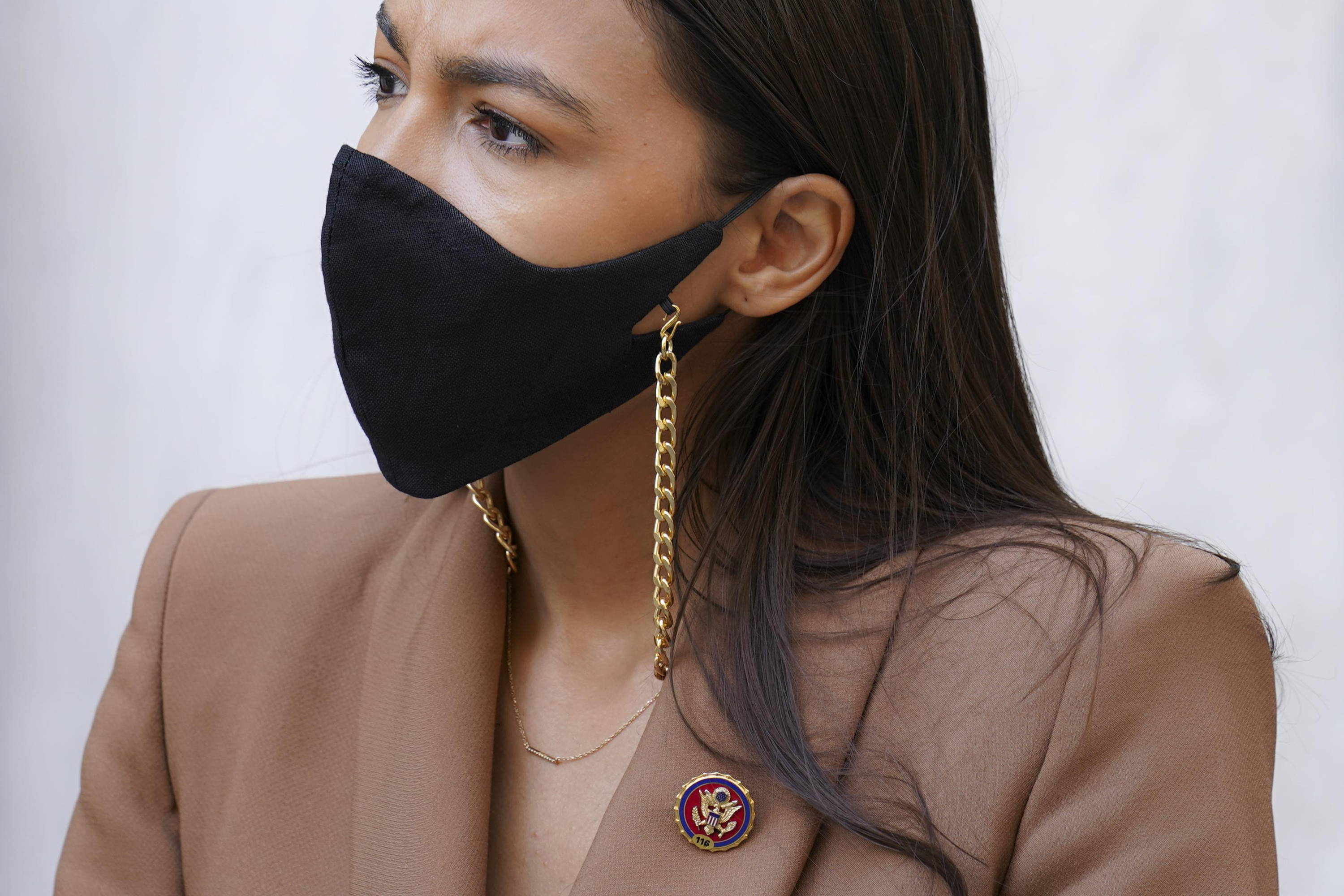 Alexandra Ocasio-Cortez wearing. aface mask with a metal chain