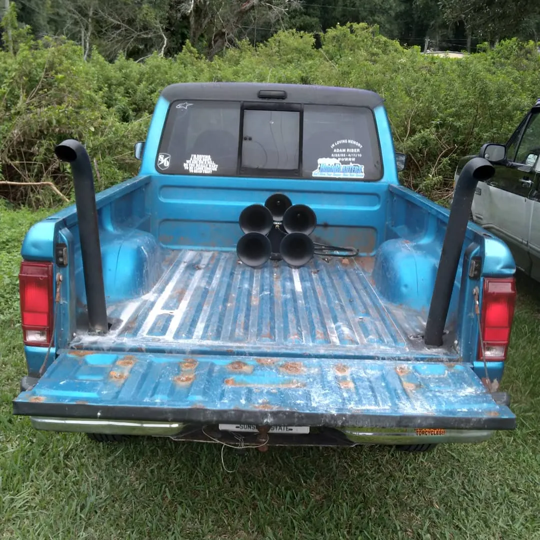 Rear view Caleb's blue Ford Ranger with tailgate down five-bell Shocker XL horns and dual vertical exhaust stacks photo 1