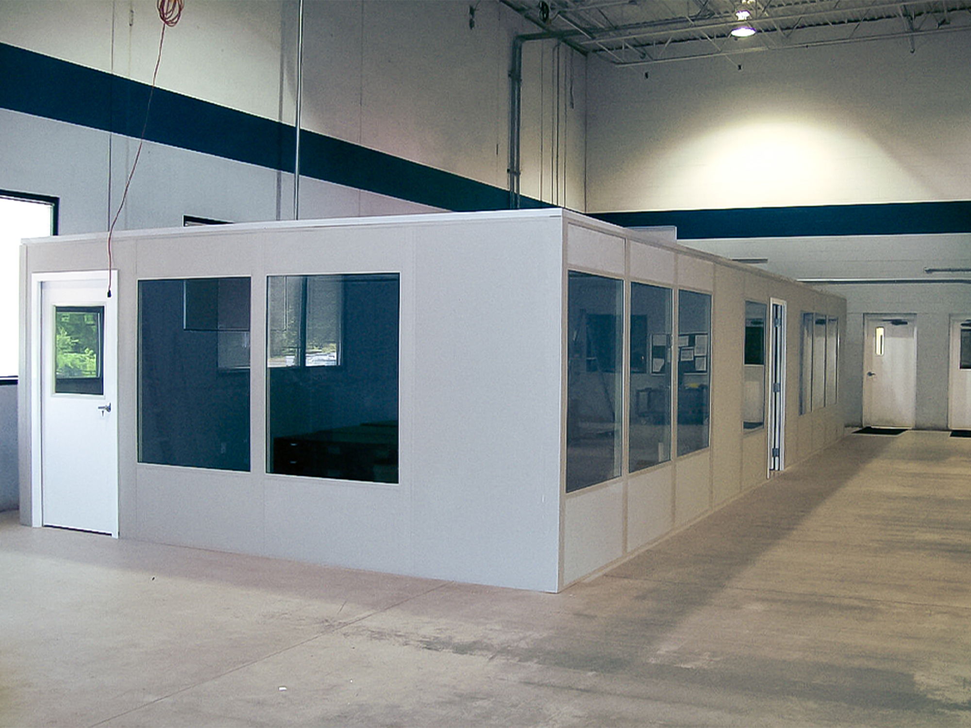 Interior of a white modular office space with windows and a door.