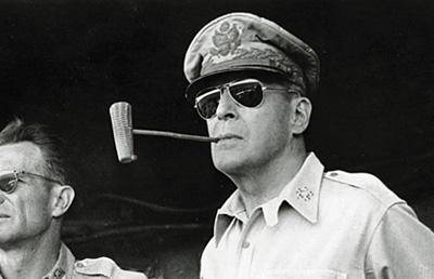 General Douglas MacArthur wearing aviator sunglasses and smoking a pipe