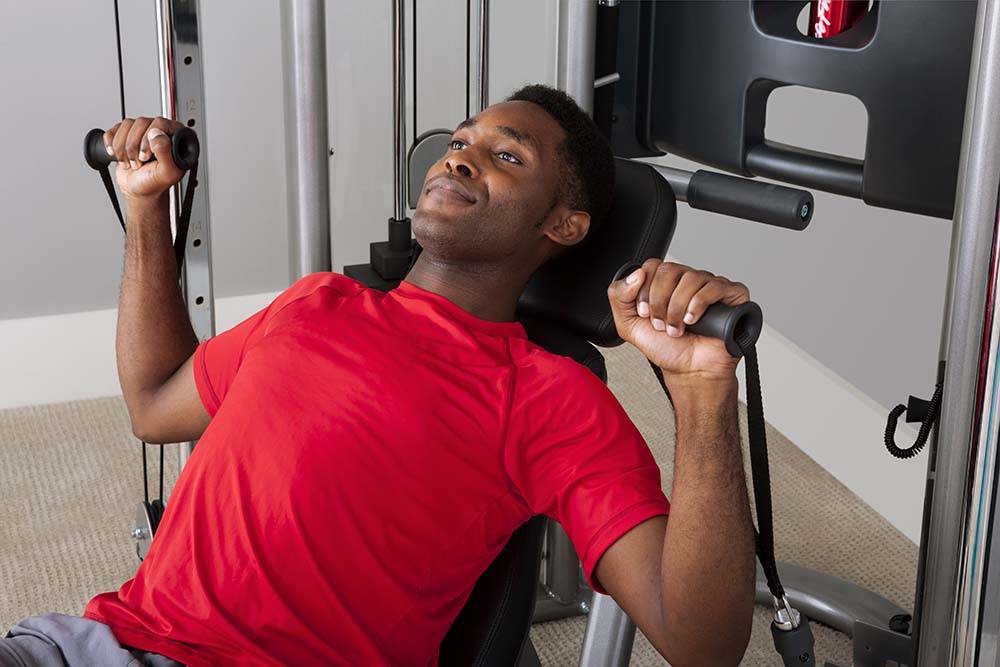 A man in a red shirt is doing exercises on a machine - image