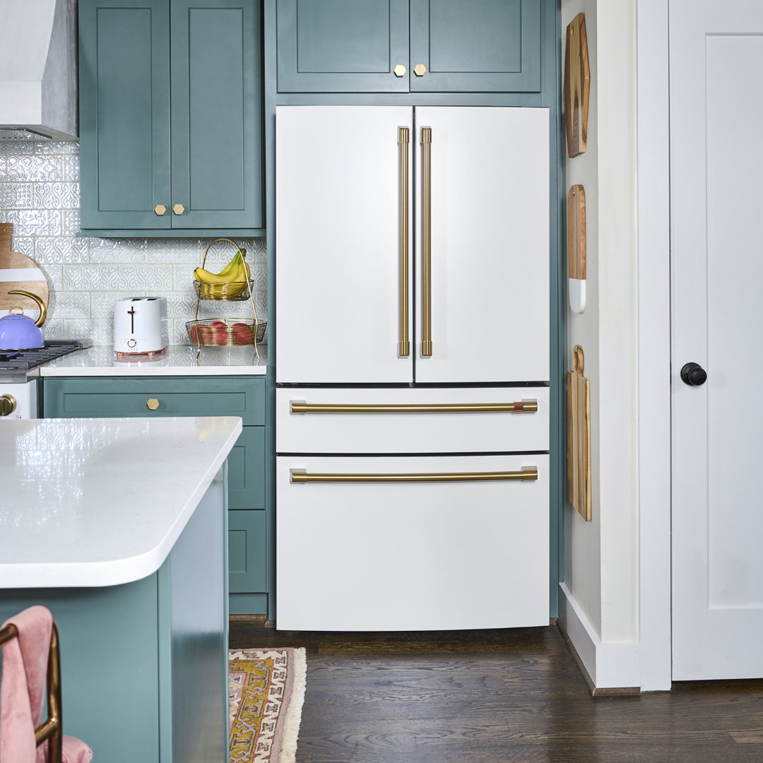Matte white white refrigerator and teal cabinetry.