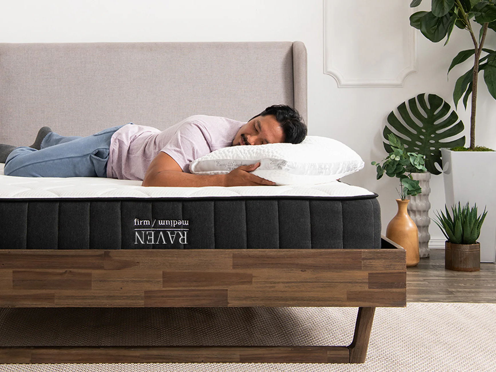 a man sleeping on a nest bedding easy breather pillow and raven flippable hybrid mattress