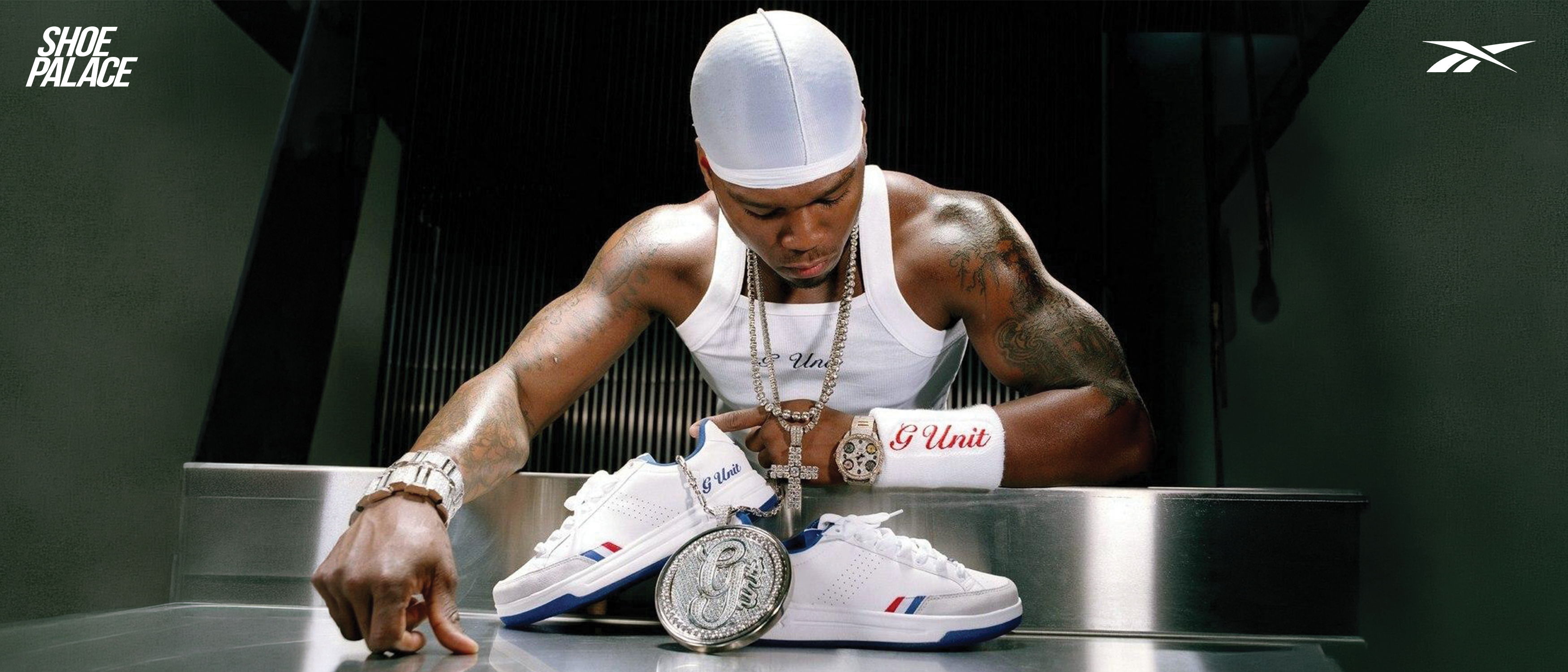 Man in white tank top examines sneakers and watches.
