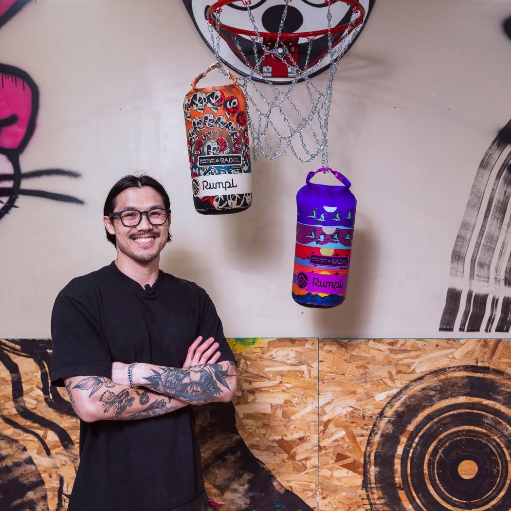 Bryce standing by a basketball hoop with two Rumpl Blankets hanging from it