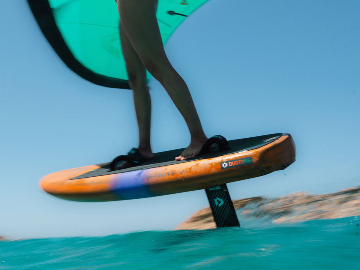 Person riding a hydrofoil board above water with a wing.