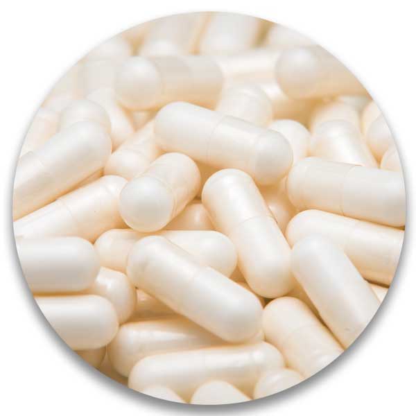 White capsules scattered on a surface, circular crop.