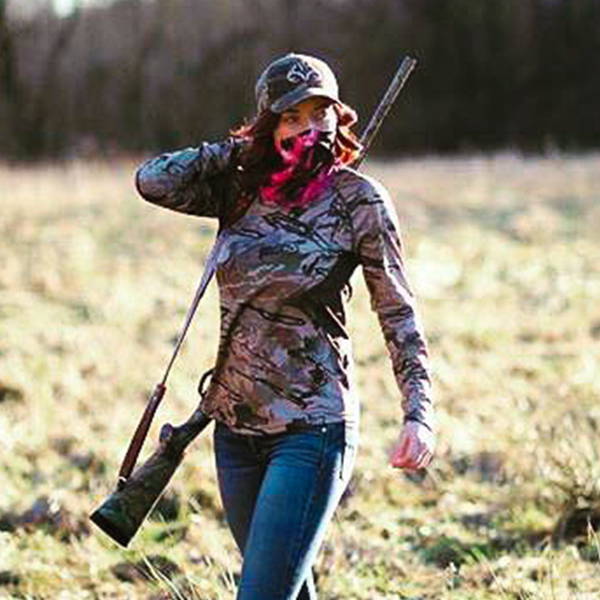 Shannon Wolff wearing a pink and black face shield over her face and shouldering a shotgun.