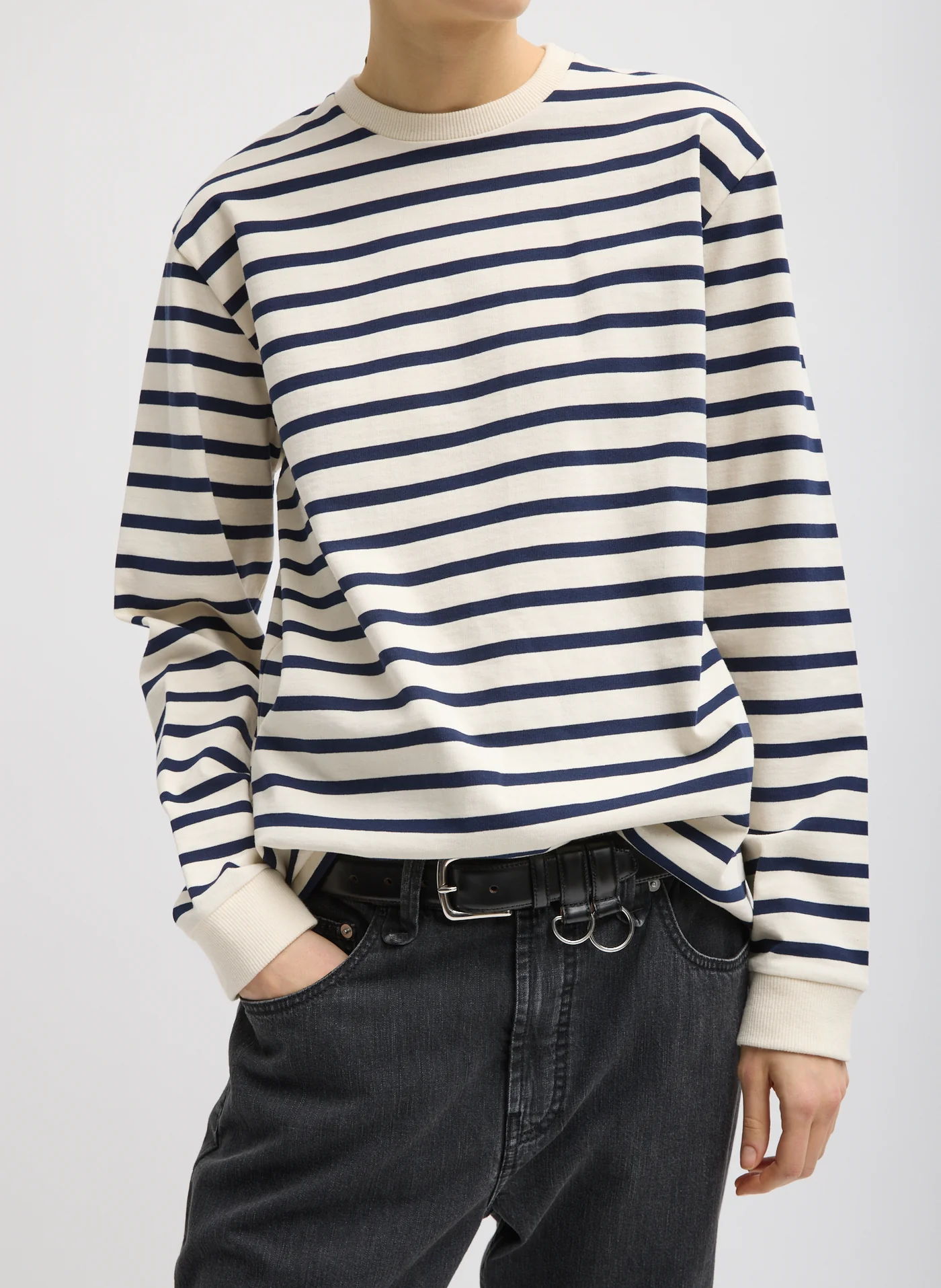 Person wearing a striped long-sleeve shirt and dark jeans.