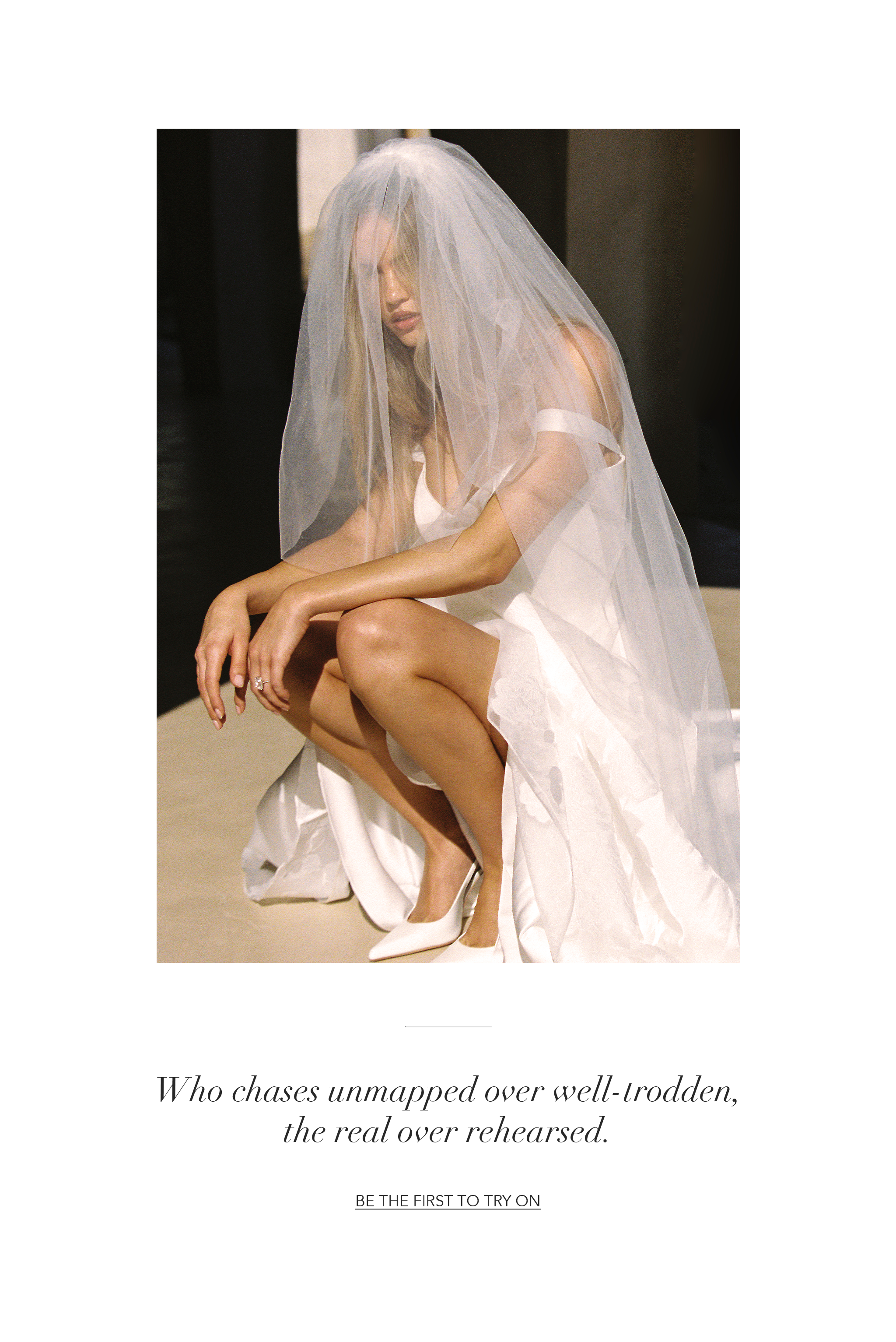 Bride in a white dress and veil, sitting thoughtfully on a surface.
