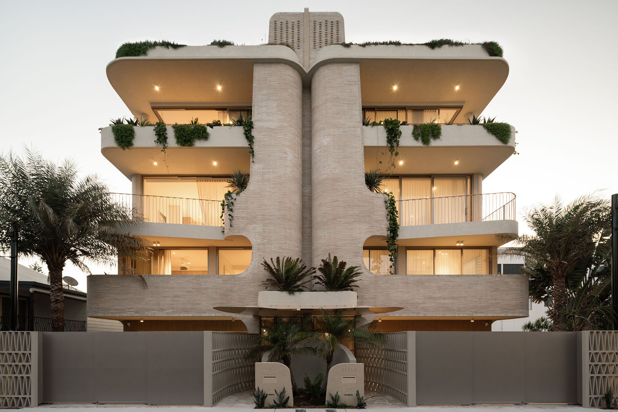 Modern architectural building with balconies and palm trees in front.