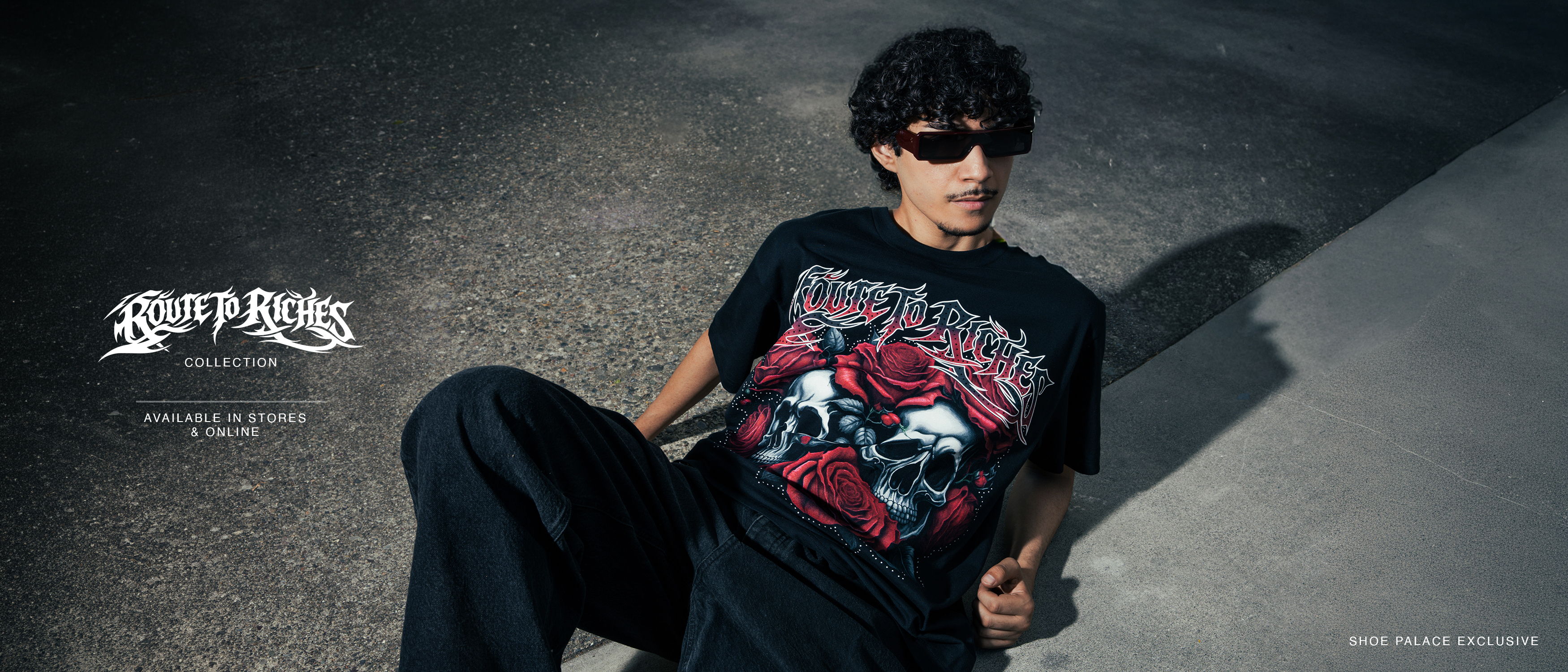 Person wearing a graphic t-shirt and sunglasses, posing on a concrete surface.