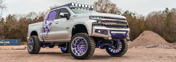 Front three-quarter Ismael's lifted silver Chevrolet Silverado Z71 with purple suspension and skull graphic photo 1