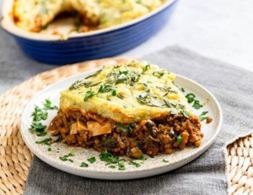 A serving of shepherd's pie on a plate with fresh herbs.