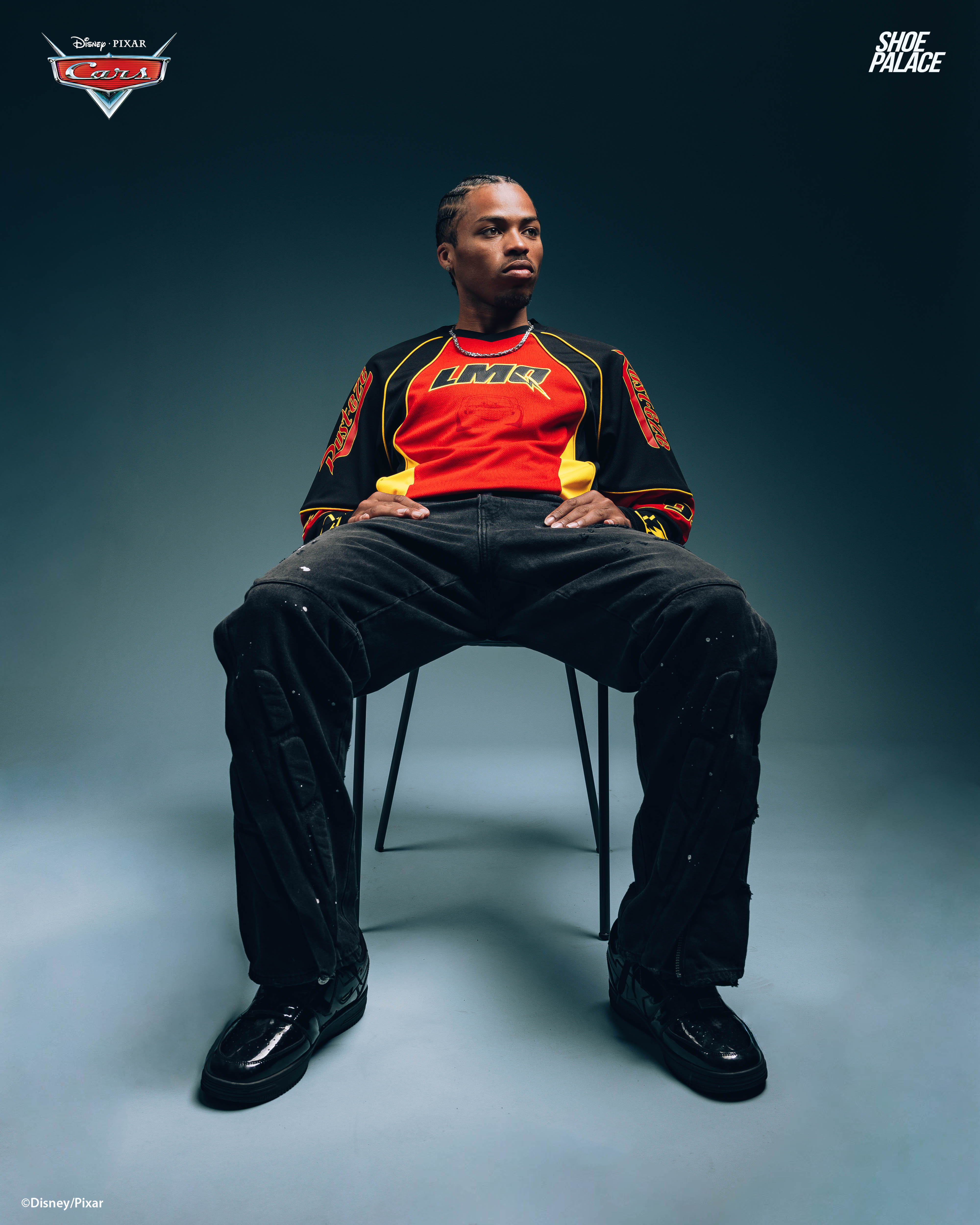 Person sitting on a chair, wearing a colorful sports outfit against a dark background.