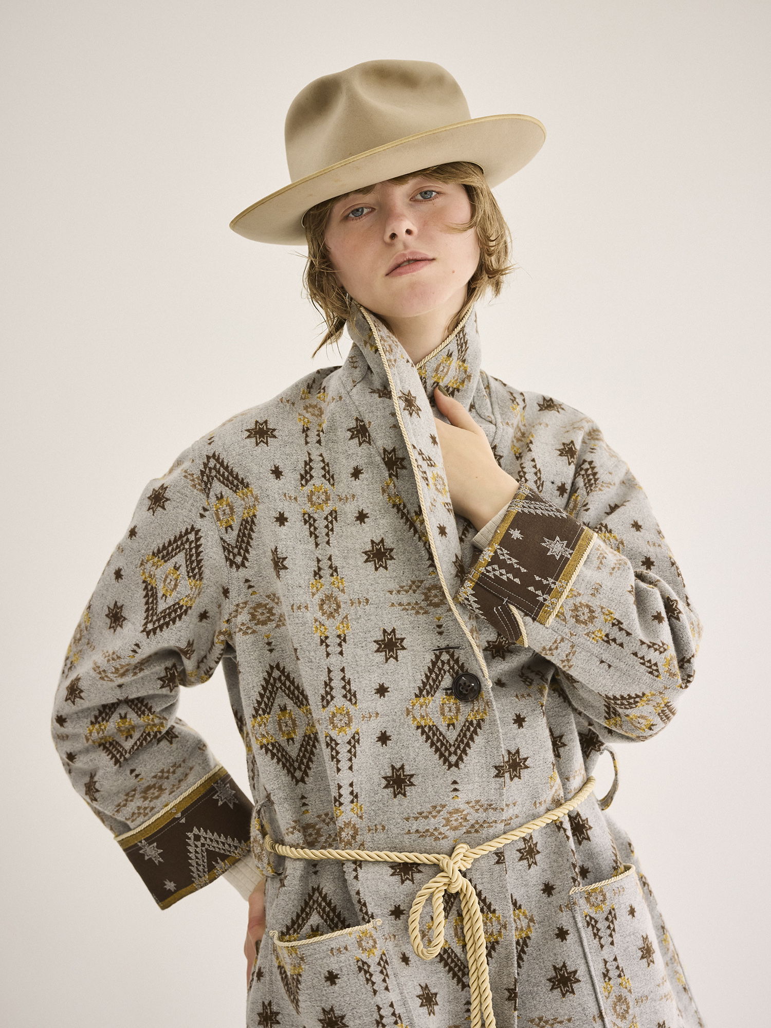 Person wearing a patterned robe and hat, posing confidently.