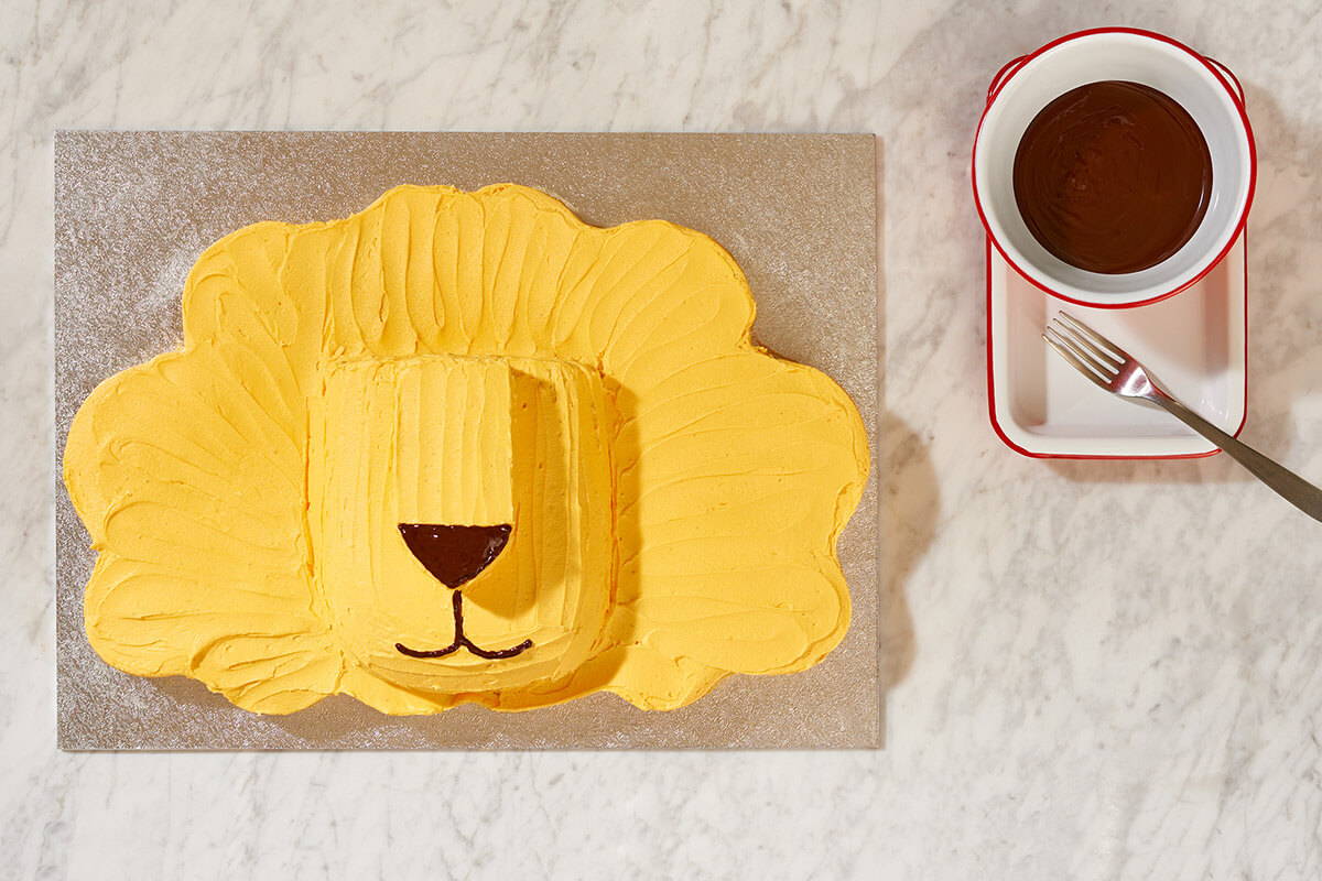 A photograph of a lion shaped cake being iced.