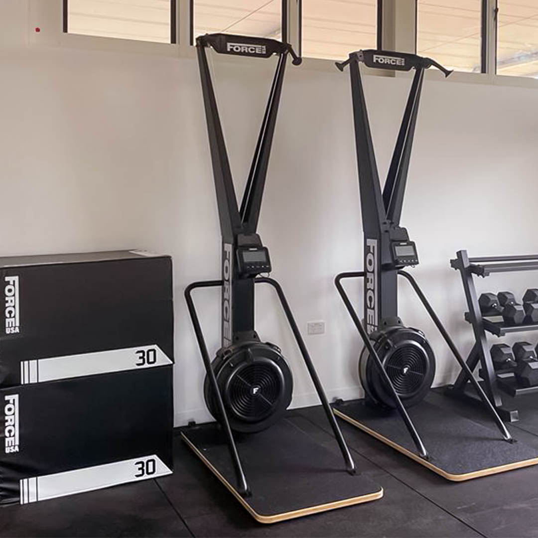 Ski trainer and plyo boxes positioned together in a high school gym fit-out, combining cardio workouts with plyometric training for dynamic fitness sessions.