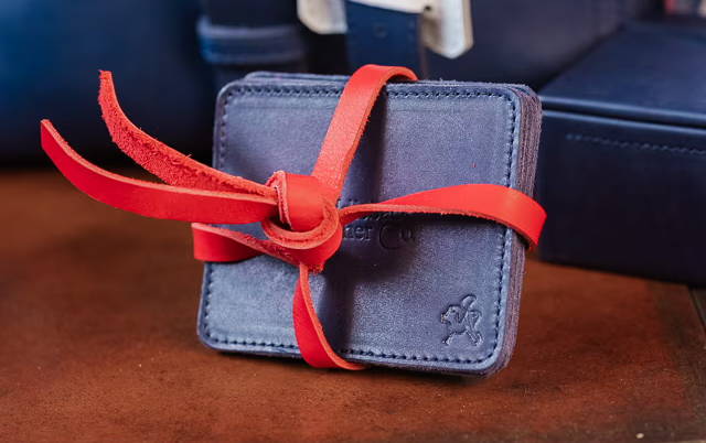 A small blue gift wrapped with a red ribbon, next to a blue bag.