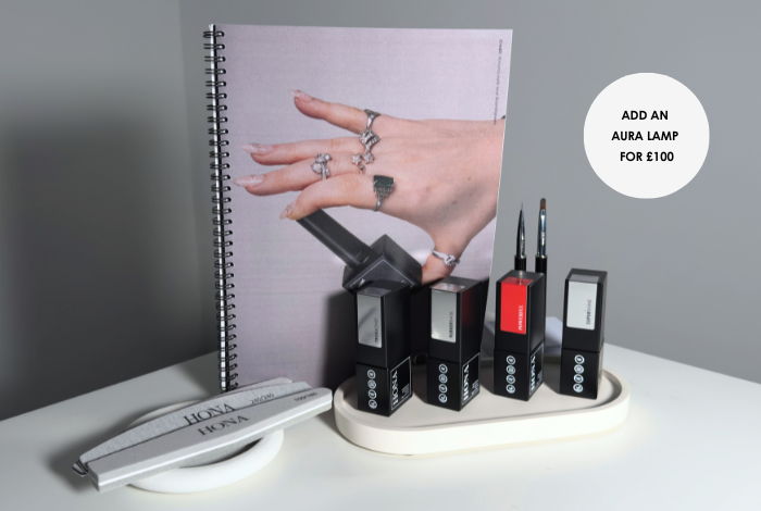 Hand holding a caliper next to measuring tools and a notebook.