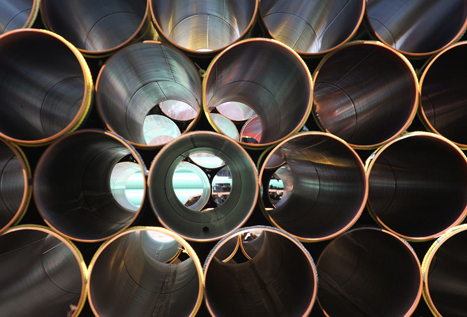 Cylindrical metal pipes arranged in a circular pattern with reflections inside.