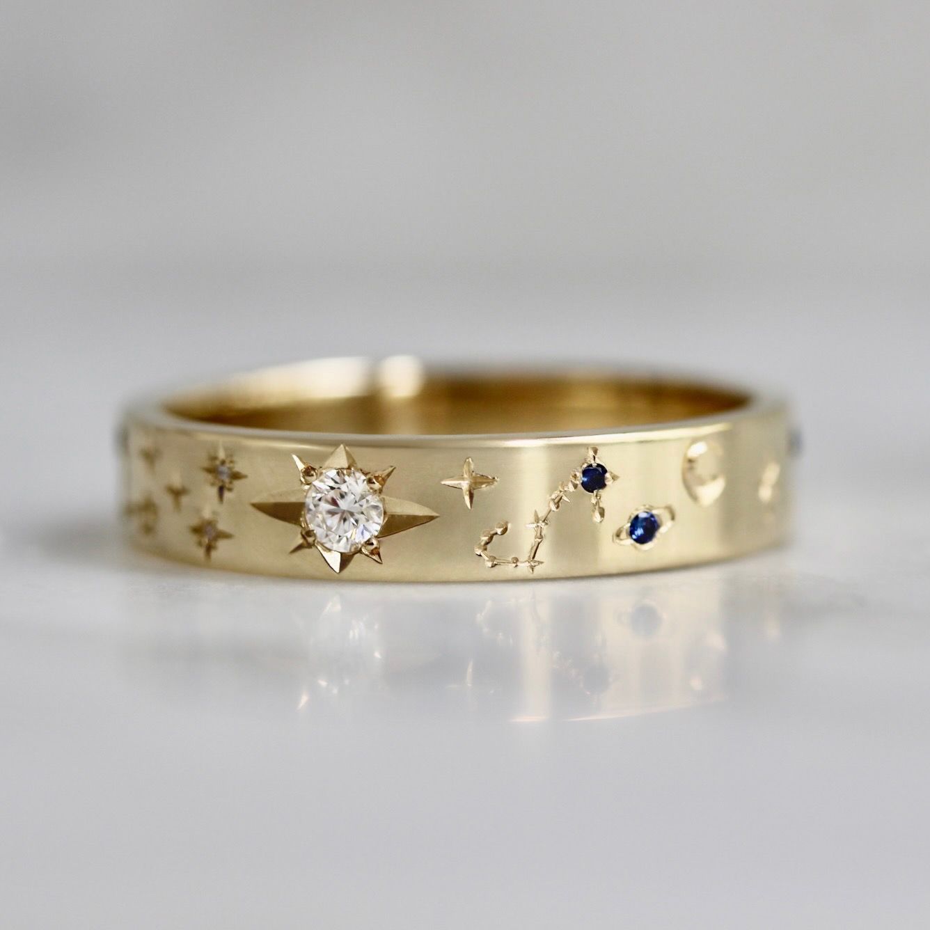 Hand-engraved wedding band with zodiac constellations, stars, and star-set diamonds and sapphires