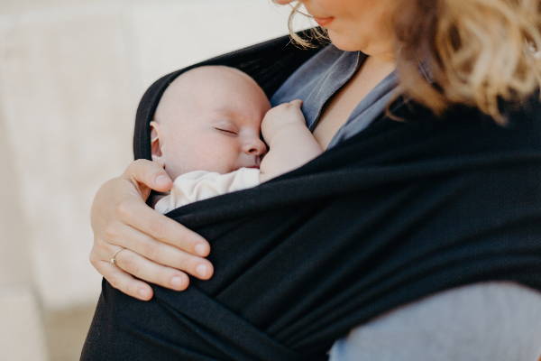 Small baby sleeping in black cotton wrap